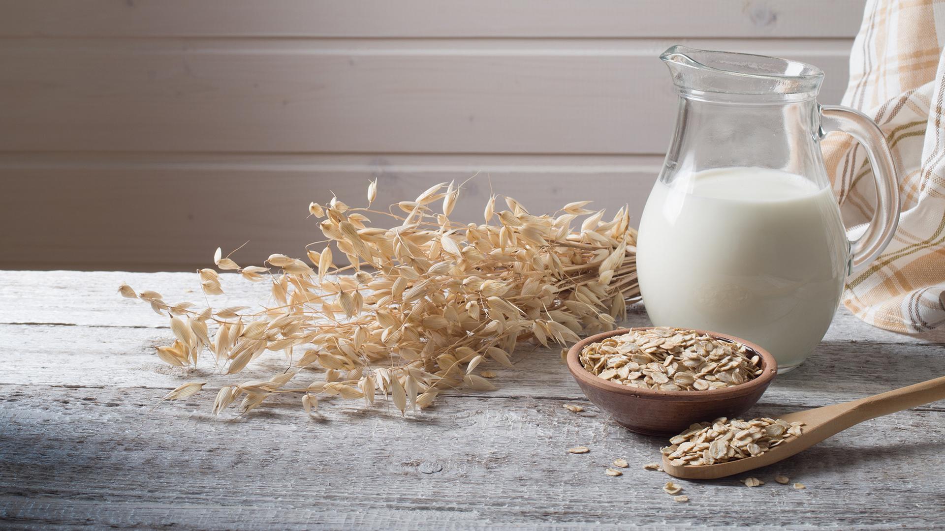 Ein Krug mit Haferdrink, daneben Haferflocken und eine Getreideähre. | Colourbox