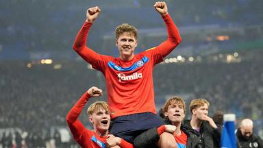 Phil Harres von Holstein Kiel jubelt mit zwei Mitspielern über den Pokal-Erfolg beim HSV.