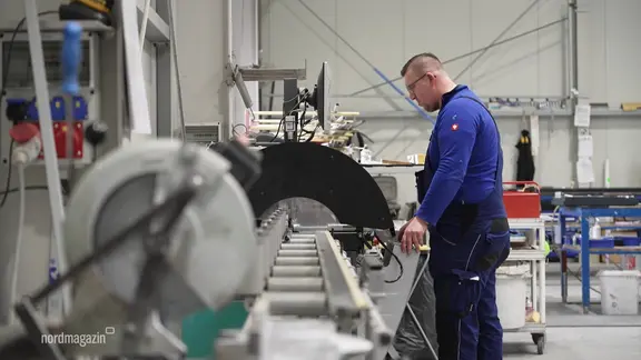 Ein Mann steht an einer Maschine in einem Metallbaubetrieb