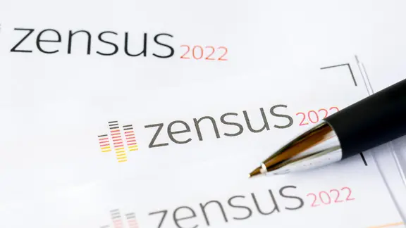 Fragebögen der Wohngebäudezählung beim Zensus 2022 mit einem Stift