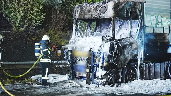 Eine Einsatzkraft der Feuerwehr löscht einen Lkw nach einem Brand auf der A28. 