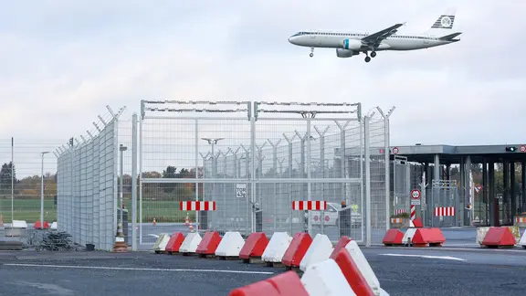 Das Tor auf das Vorfeld des Hamburger Flughafens ist geschlossen, eine Maschine der Fluggesellschaft Aer Lingus setzt zur Landung an.