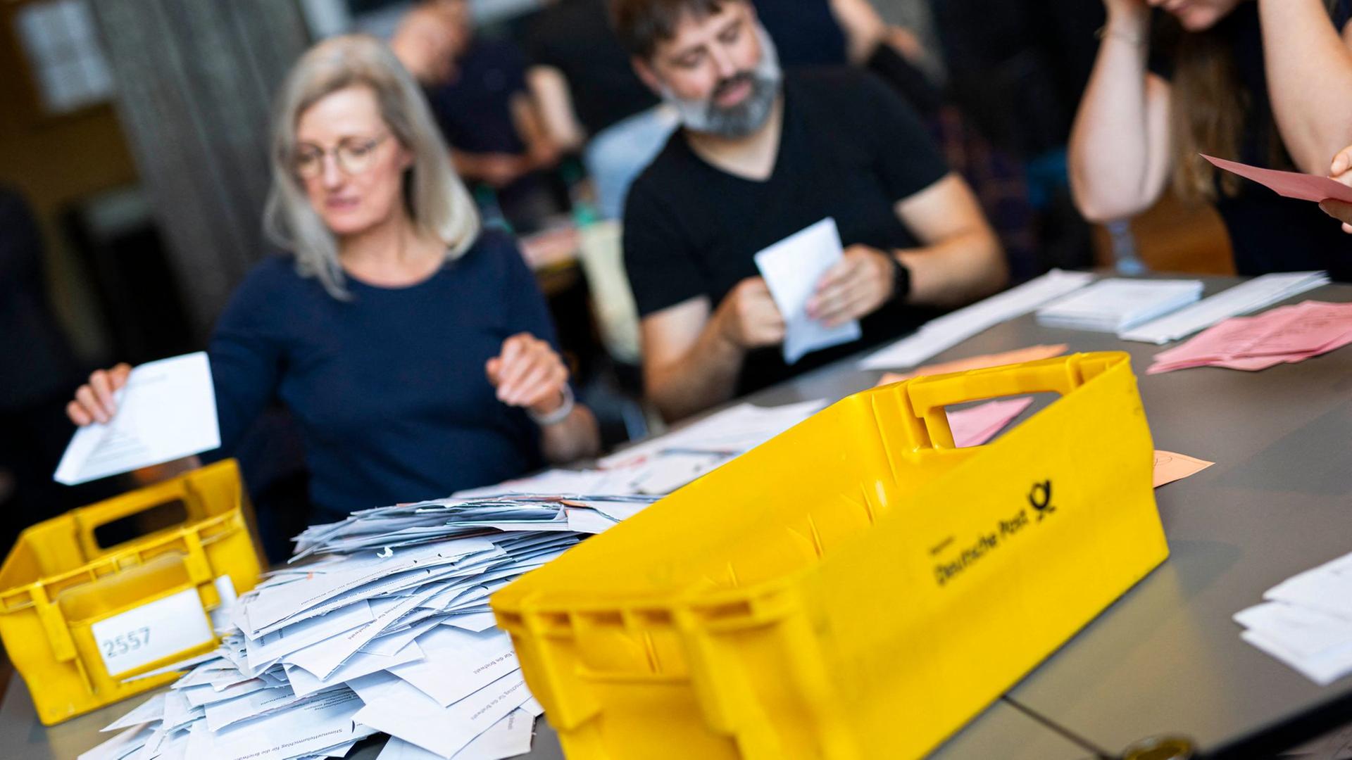 Eine Wahlhelferin schüttet nach der Wahl Briefwahlunterlagen auf einen Tisch. | dpa-Bildfunk, Michael Matthey