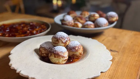 Teigbällchen mit Zwetschgenkompott auf einem weißen Teller serviert