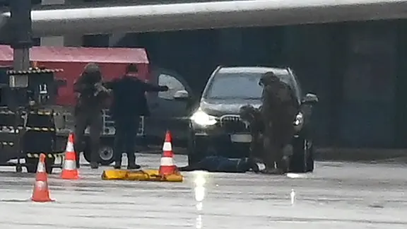 Ein Mann liegt auf dem Flughafen auf dem Boden, umringt von Polizeikräften.