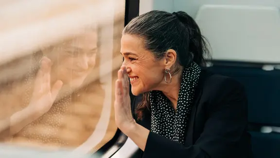 Frau winkt aus dem Zugfenster