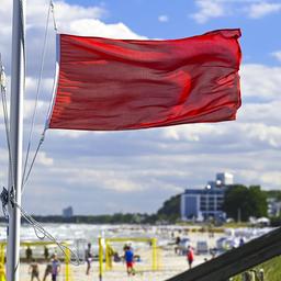 Eine rote Flagge weht am Ostseestrand von Scharbeutz in Schleswig-Holstein.