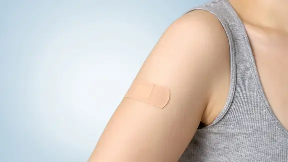 Ein Pflaster klebt auf dem Arm einer jungen Frau.