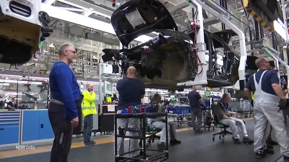 VW-Mitarbeiter arbeiten an einer Fertigungsstraße.