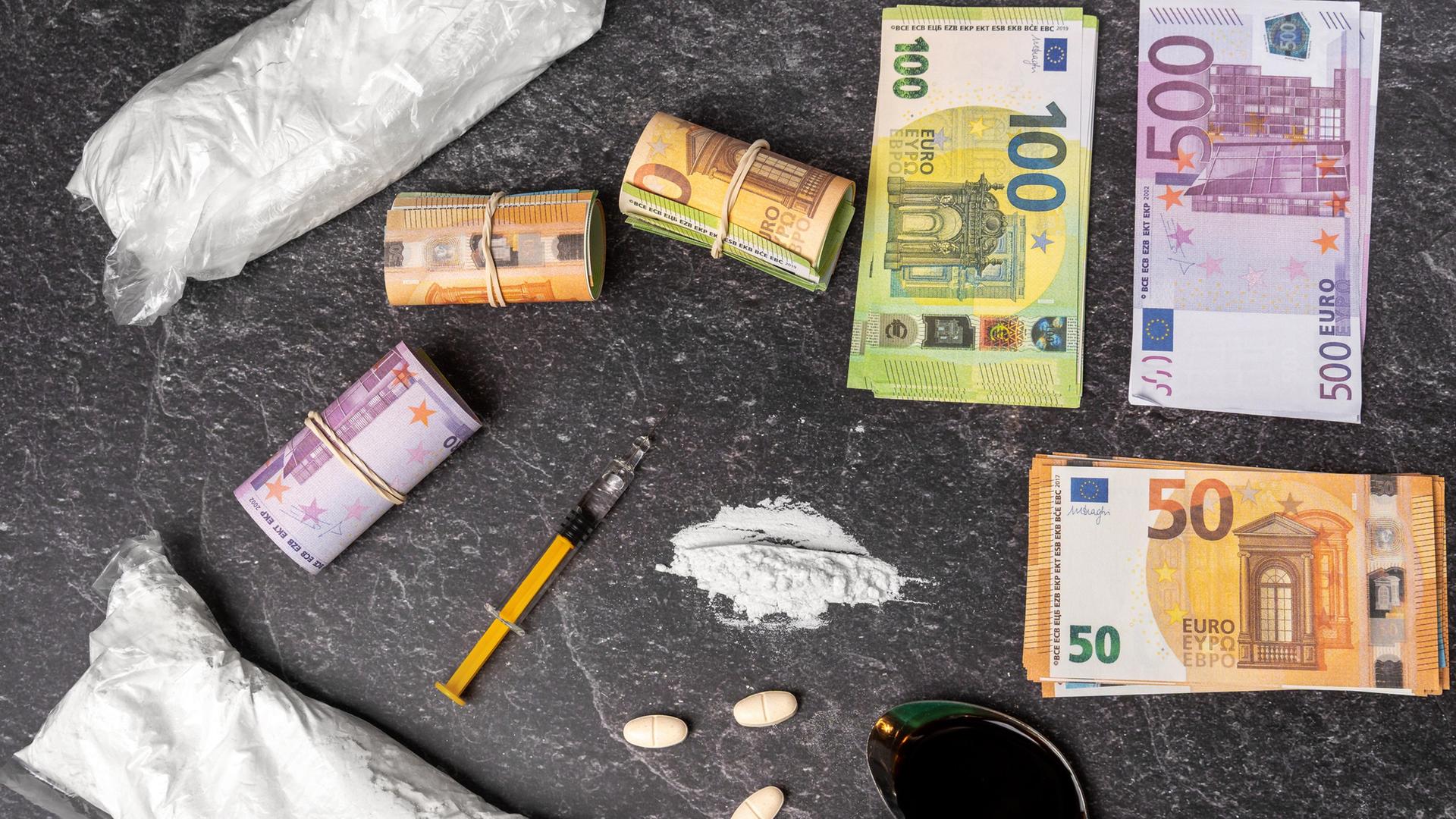 Drogen, Spritze, Tabletten und Geldscheine liegen nebeneinander und zeigen den illegalen Drogenhandel.  | picture alliance / CHROMORANGE | MICHAEL BIHLMAYER