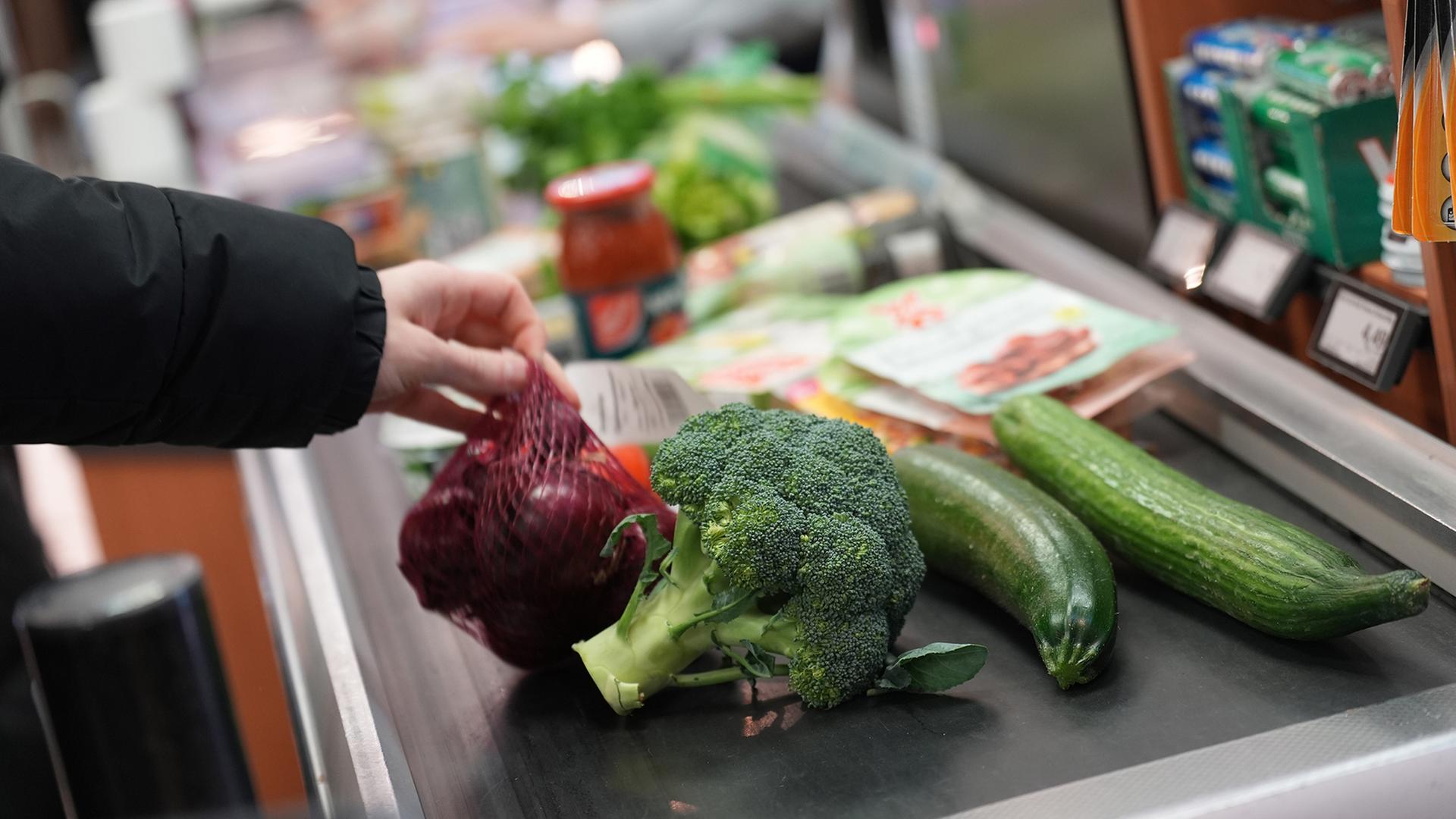 Ein Mann legt seinen Einkauf auf das Laufband an einer Kasse in einem Supermarkt | picture alliance/dpa / Marcus Brandt