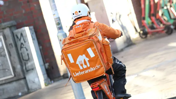 Ein Kurier von Lieferando fährt mit einem Fahrrad durch die Hamburger Innenstadt.