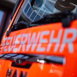 Eine Einsatzkraft der Feuerwehr steht neben einem Einsatzfahrzeug der Feuerwehr.
