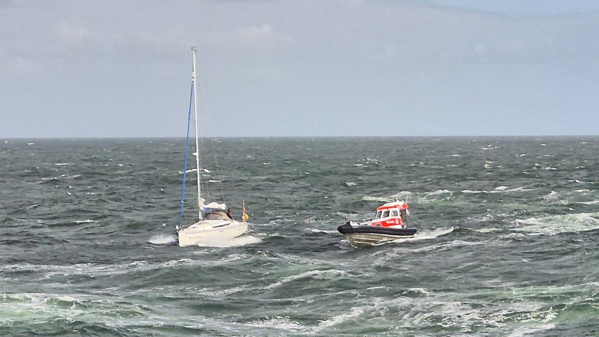 Ein Rettungsboot fährt zu einem Segelboot. | Die Seenotretter - DGzRS