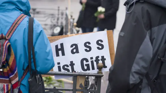 "Hass ist Gift" steht auf einem von Regen durchweichten Schild