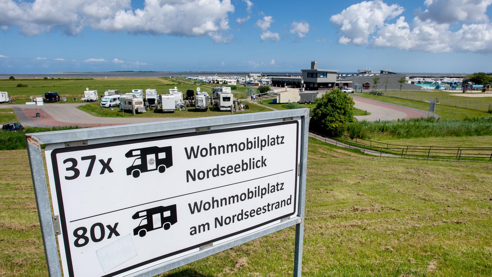 Ein Schild auf dem Deich weist bei sonnigem Wetter auf einen Wohnmobilstellplatz mit Blick auf die Nordsee hin. | picture alliance / dpa, Hauke-Christian Dittrich