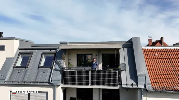 Ein Mann steht auf einem Balkon mit einer Solaranlage.