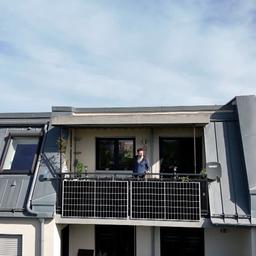 Ein Mann steht auf einem Balkon mit einer Solaranlage.