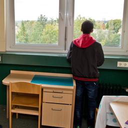 Ein Junge steht in einem Zimmer und schaut aus dem Fenster.