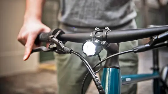 Ein Vorderlicht und der Lenker eines Fahrrads, im Hintergrund eine Person. | picture alliance / dpa Themendienst, Robert Guenther Ein Vorderlicht und der Lenker eines Fahrrads, im Hintergrund eine Person.