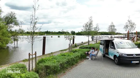 Anna und Niklas Kröpke sitzen vor ihrem ausgebauten Camper Van und schauen auf die Elbe.