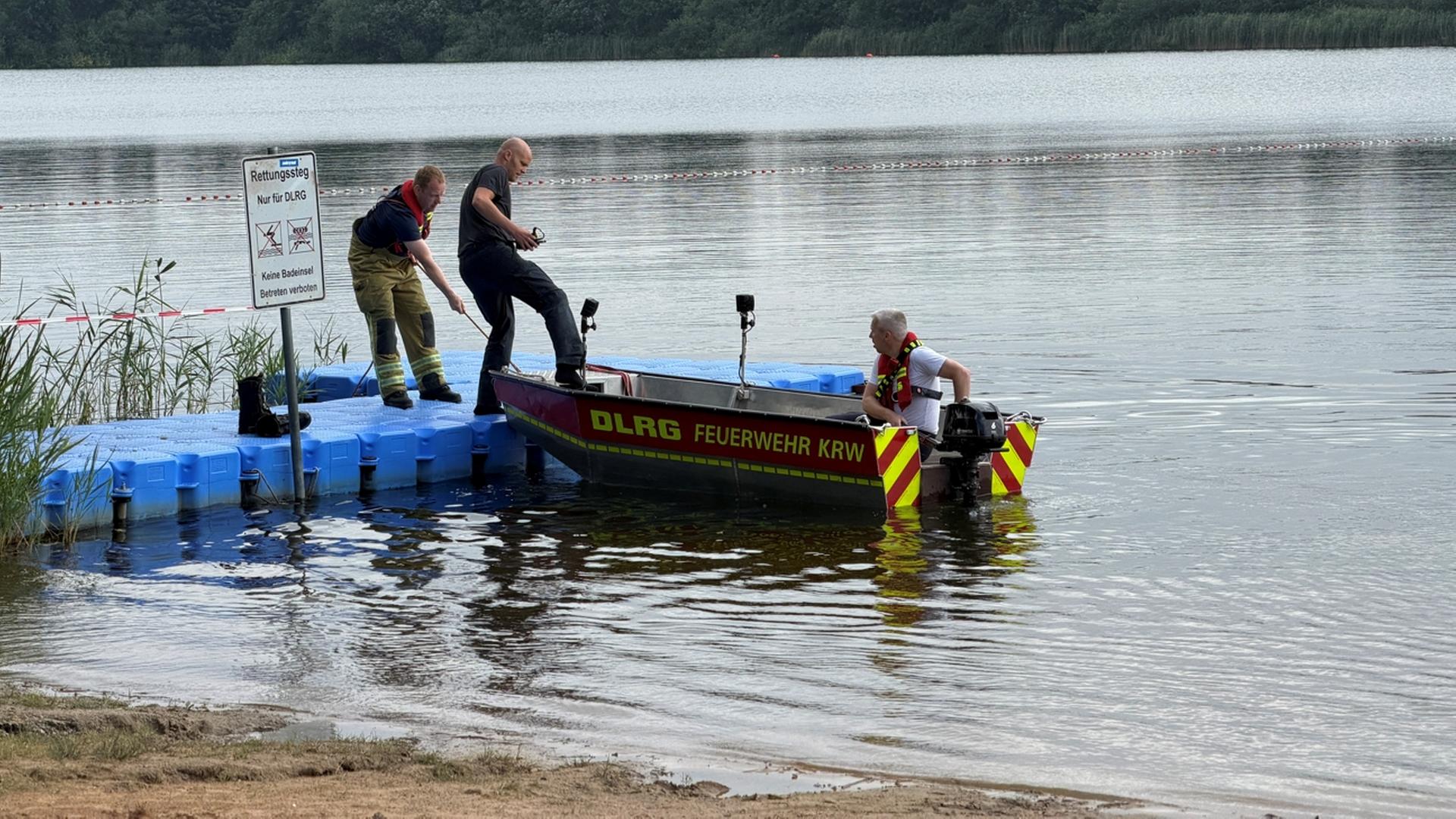 Ein Retter liegt mit einem DLRG-Boot an einem Steg. Zwei Feuerwehrleute halten das Boot. | Ortsfeuerwehr Isernhagen, Tobias Goth