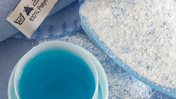 Ein Becher mit Flüssigwaschmittel und einer mit Waschpulver