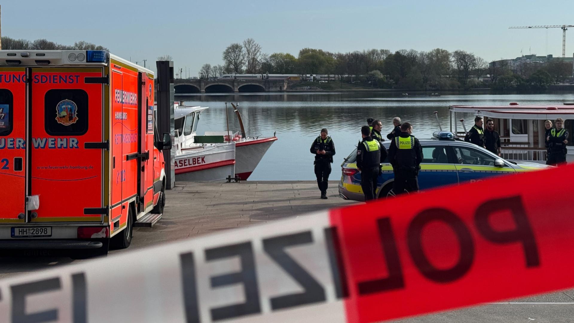 Polizisten und Einsatzfahrzeuge von Polizei und Feuerwehr stehen an der Binnenalster, wo eine Leiche gefunden wurde. | picture alliance/dpa/Leonie Asendorpf