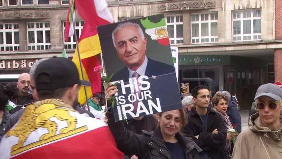 Eine Demonstrantin hält ein Bild von  Reza Pahlavi hoch.