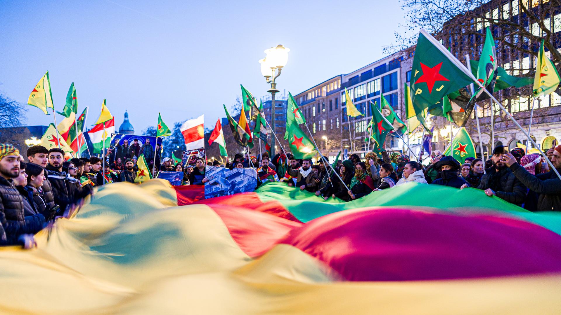 Mehrere Demonstranten halten eine große Fahne auf dem Opernplatz in Hannover. | picture alliance/dpa-Bildfunk, Moritz Frankenberg