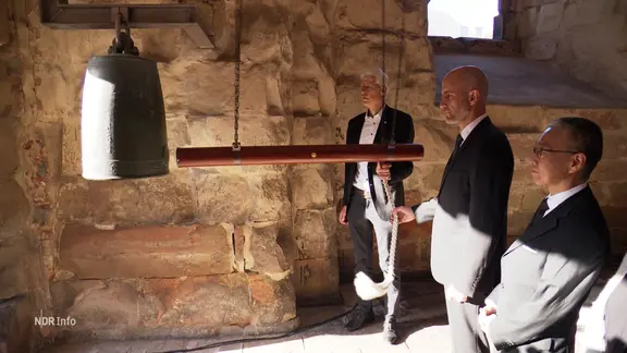 Bei einer Gedenkstunde wird eine Glocke geläutet.