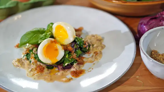 Senfeier mit Spinat und Chutney auf einem Teller angerichtet.