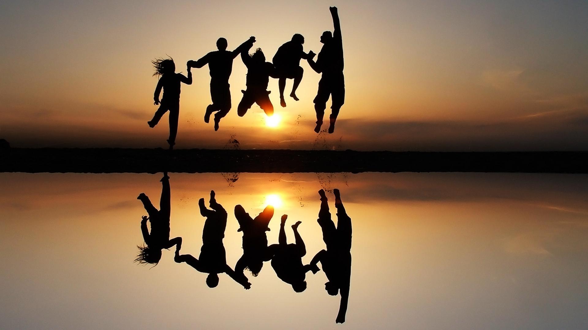 Fünf Jugendliche springen am Strand dem Sonnenuntergang entgegen. | Photocase, Emanoo