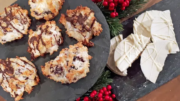 Kokos-Makronen und Mandelnougat liegen auf Schieferplatten.