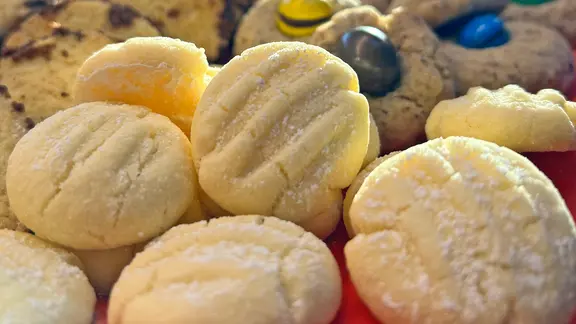 Mit Puderzucker bestäubte Kekse, dahinter andere Kekssorten.