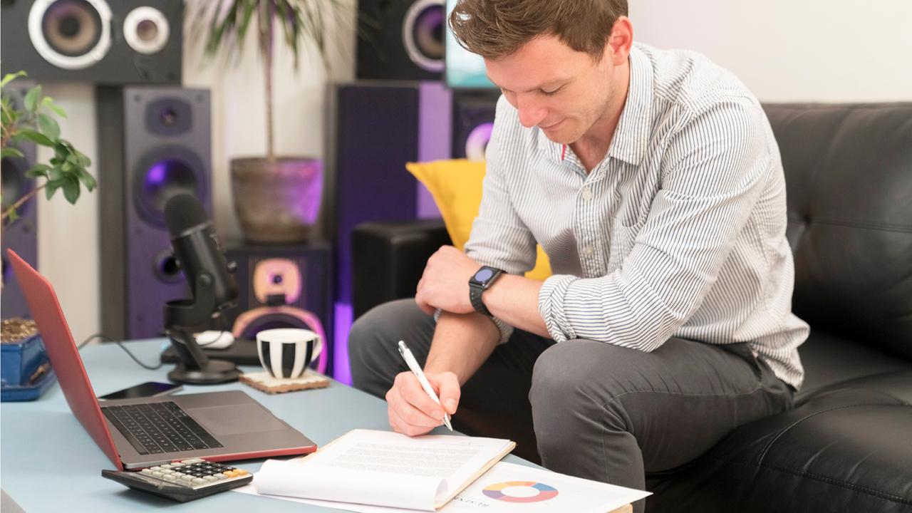 Ein Mann sitzt auf einem Sofa und geht Dokumente durch. 