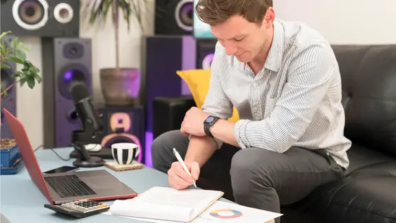 Ein Mann sitzt auf einem Sofa und geht Dokumente durch. 