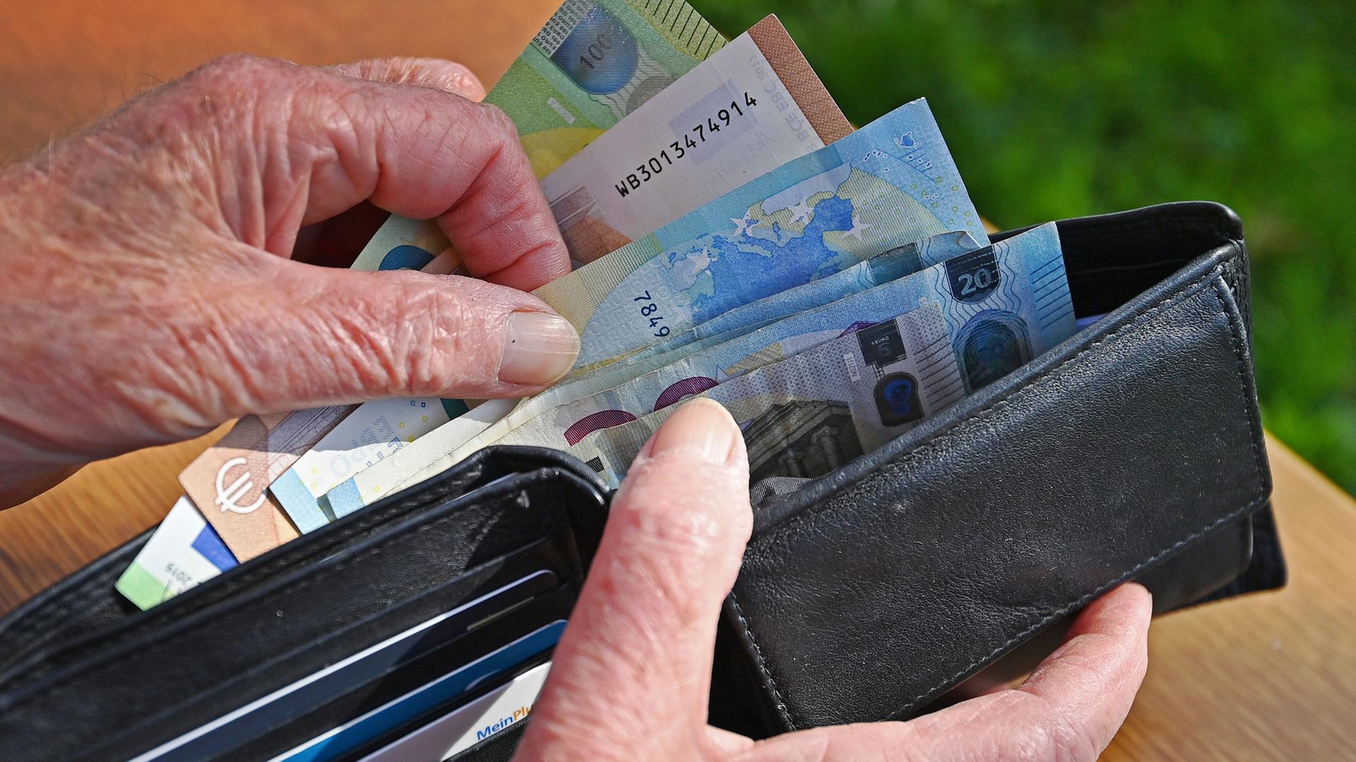 Die Hand einer älteren Person blättert in einem Portemonnaie. | picture alliance / SvenSimon, Frank Hoermann