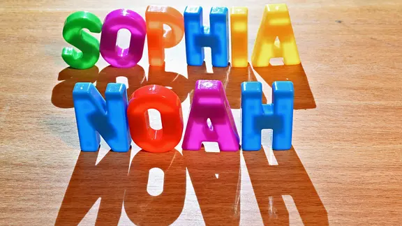 Die Vornamen Sophia und Noah stehen in bunten Plastikbuchstaben geschrieben auf einem Tisch.
