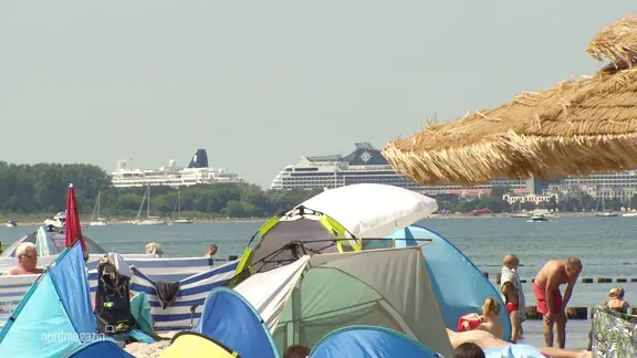Menschen mit Strandmuscheln genießen das Sommerwetter am Meer in Markgrafenheide.