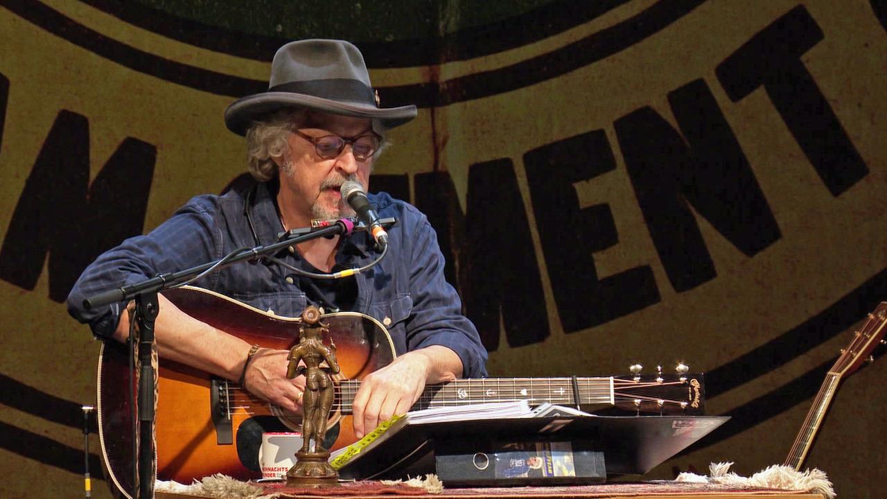 Der Musiker Wolfgang Niedecken mit einer Gitarre und Mikro auf der Bühne