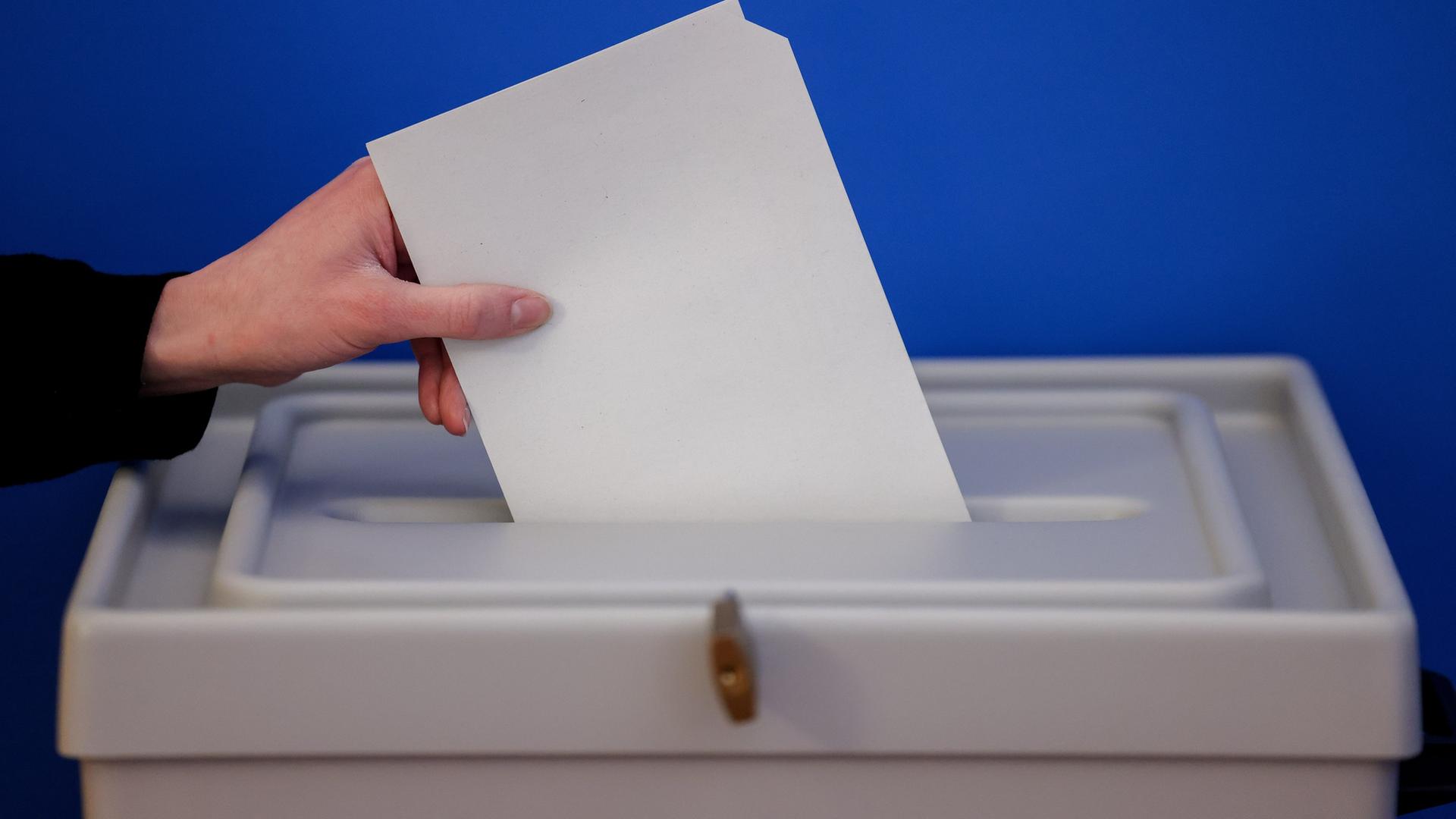 Eine Hand legt einen Wahlzettel in eine Wahlurne. | picture alliance/dpa, Jan Woitas