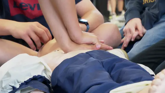 Schüler*innen erproben eine Reanimation an einer Puppe.