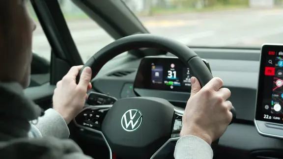 Ein Mann sitzt am Steuer eines VW E-Autos.