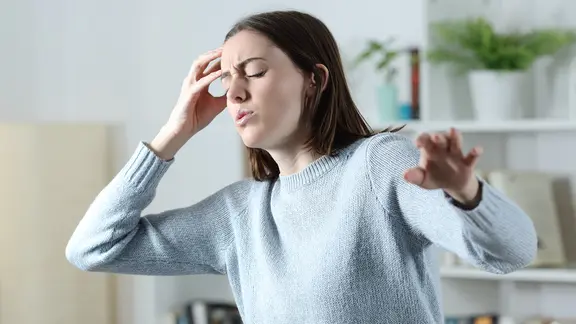 Frau mit Kreislaufproblemen fasst sich an Kopf und sucht nach Balance (Bild: colourbox.de)