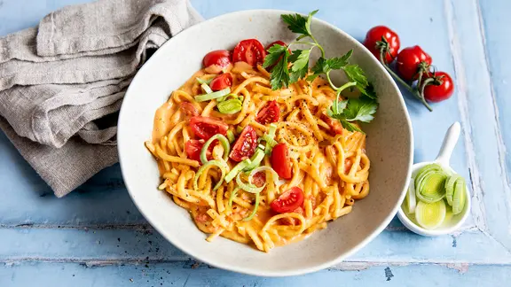 Spätzle mit Lauch und Tomaten in einer Schüssel.