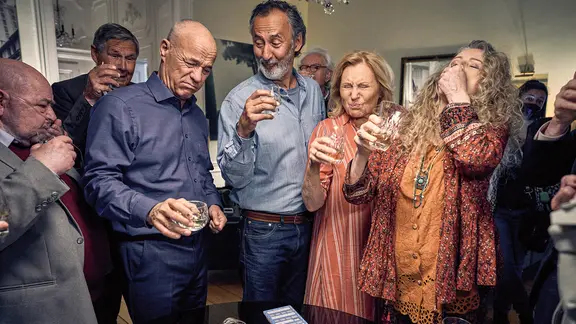 Szene aus dem Film "Enkel für Fortgeschrittene": Mehrere ältere Personen mit einem Glas in der Hand stoßen gemeinsam an.