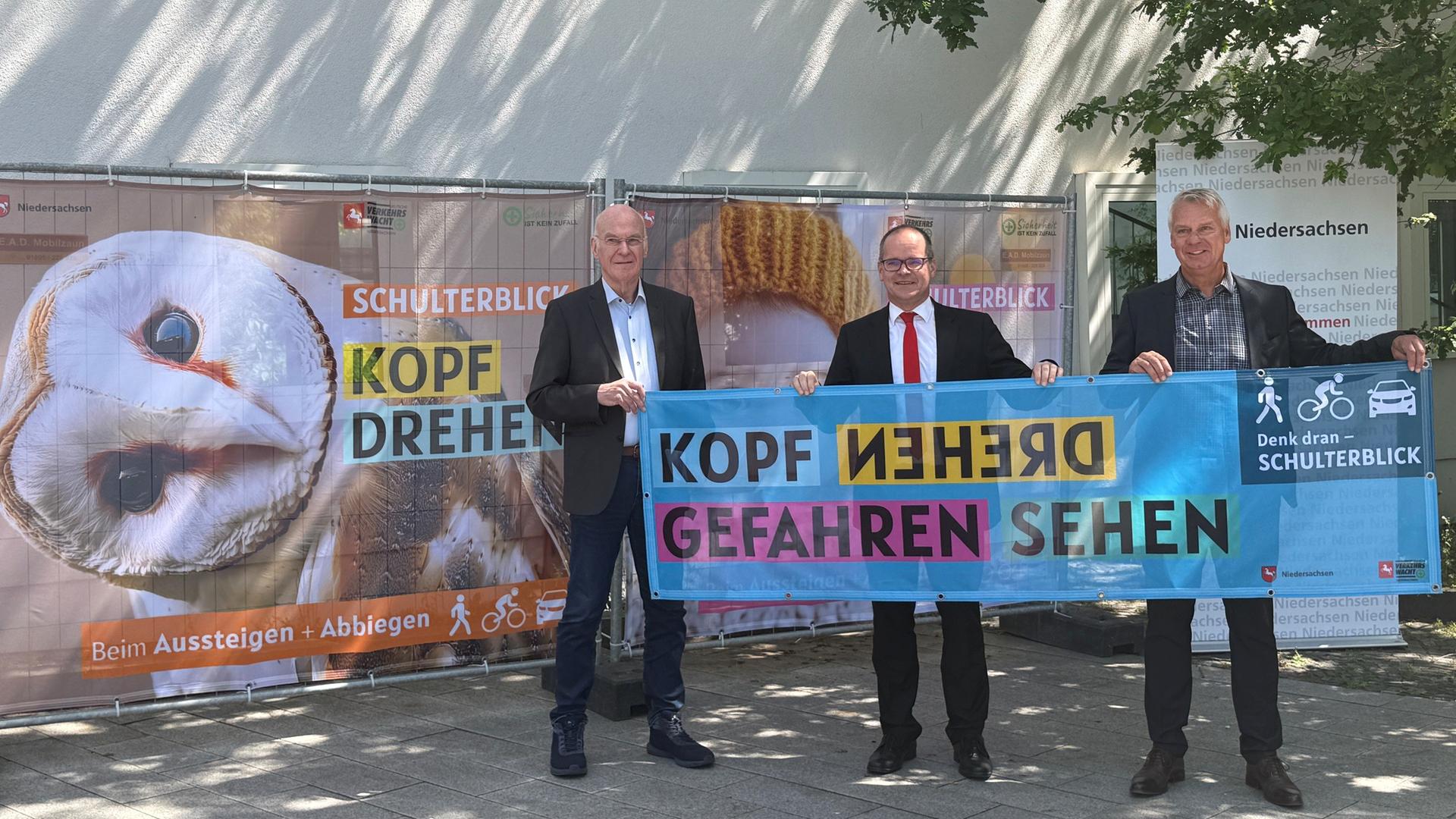 Drei Männer halten ein Plakat zum Thema 