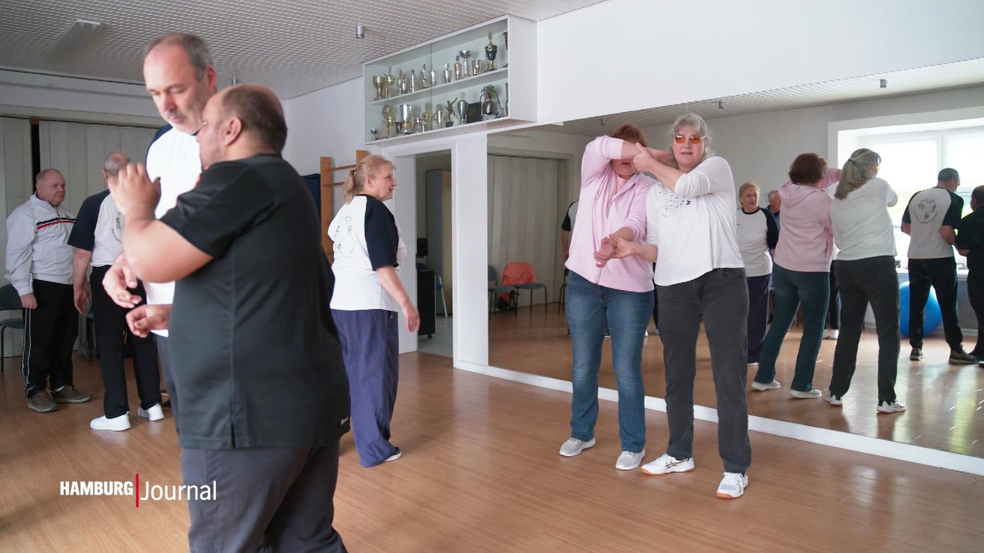 Blinde Frauen und Herren trainieren in einem Raum Selbstverteidigung. | Screenshot