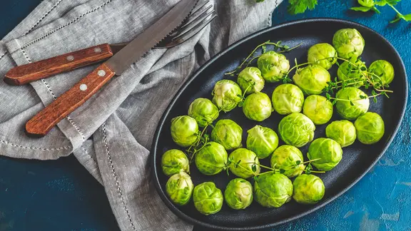 Ein Teller mit Rosenkohl, daneben Besteck. 